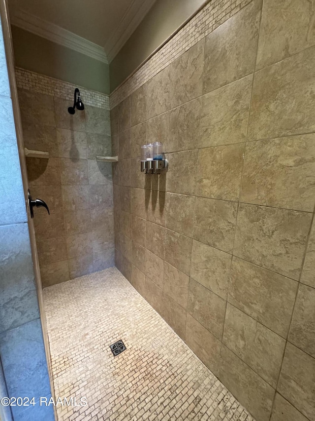 bathroom with tiled shower and crown molding