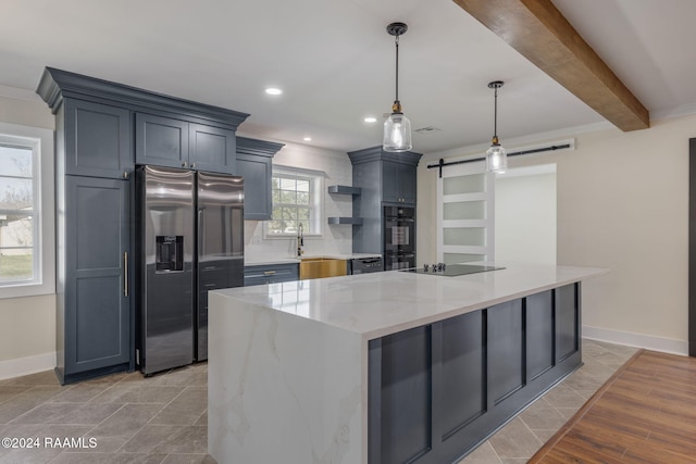 kitchen featuring beam ceiling, a barn door, light stone counters, decorative light fixtures, and black appliances