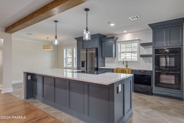 kitchen with pendant lighting, backsplash, black appliances, sink, and a kitchen island