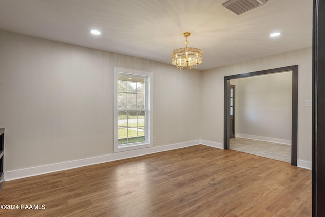 unfurnished room featuring wood-type flooring and an inviting chandelier