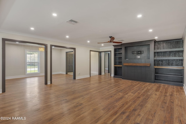 unfurnished living room with ceiling fan, wood-type flooring, crown molding, and built in shelves