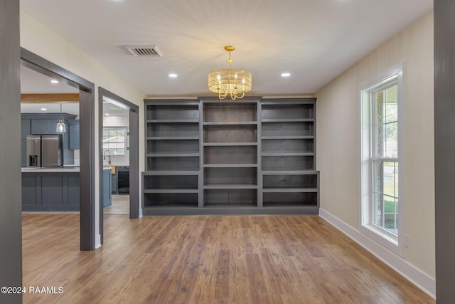 unfurnished dining area featuring hardwood / wood-style flooring and an inviting chandelier