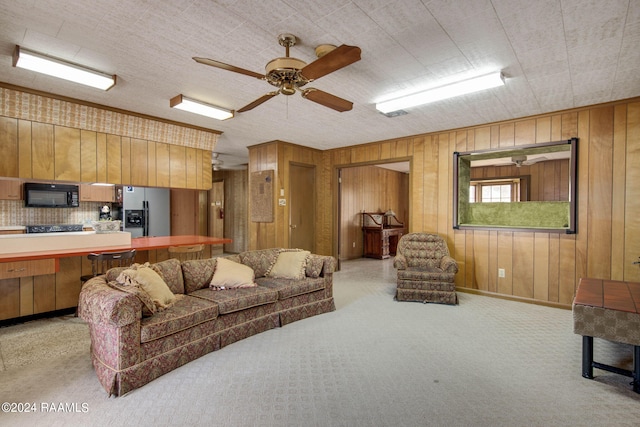 living room with light colored carpet, ceiling fan, and wood walls