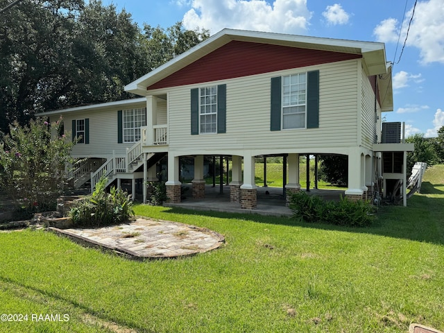 rear view of house featuring a yard, central AC unit, and a patio area