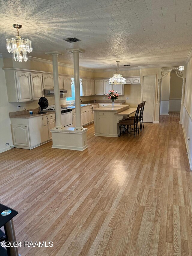 kitchen featuring pendant lighting, light wood-type flooring, decorative columns, and a kitchen island