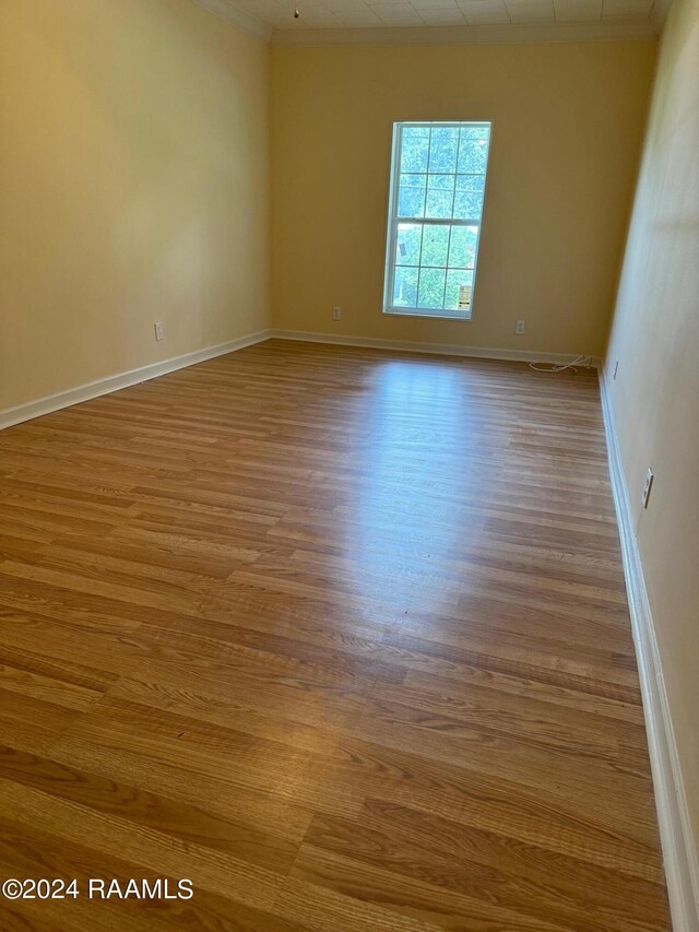 empty room with light wood-type flooring and ornamental molding