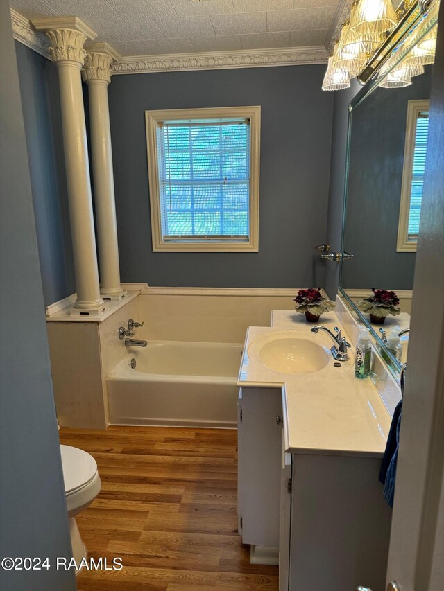 bathroom with a bath, hardwood / wood-style floors, ornamental molding, vanity, and toilet