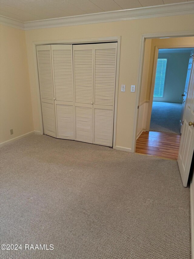 unfurnished bedroom featuring a closet, ornamental molding, and light hardwood / wood-style flooring