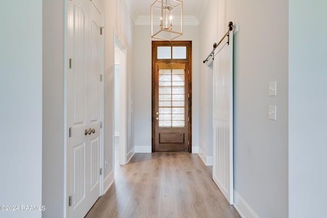 foyer entrance with a notable chandelier, light hardwood / wood-style flooring, crown molding, and a barn door