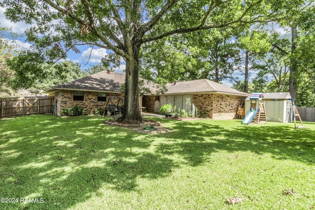 192 Tillou Andrus Dr, Opelousas, LA 70570 - back of house with a lawn, a fenced backyard, brick siding, and a playground