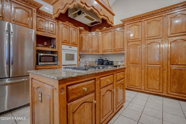 kitchen featuring light stone countertops, light tile patterned floors, appliances with stainless steel finishes, and a kitchen island