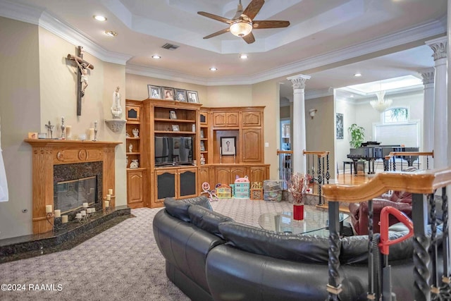 carpeted living room featuring ornamental molding, a high end fireplace, decorative columns, and a raised ceiling