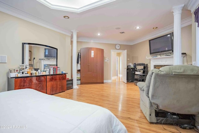 bedroom featuring decorative columns, light hardwood / wood-style floors, and crown molding