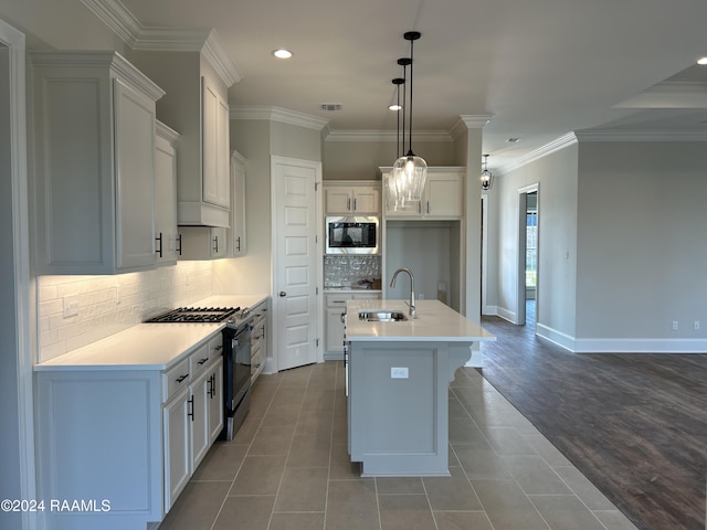 kitchen with hanging light fixtures, sink, an island with sink, appliances with stainless steel finishes, and white cabinetry