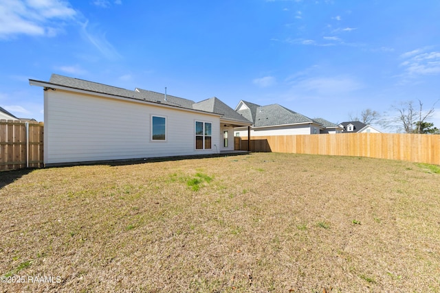 rear view of property with a fenced backyard and a yard