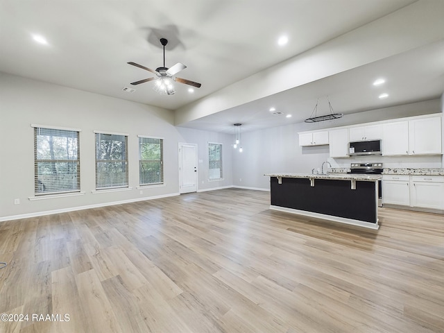 kitchen featuring light hardwood / wood-style floors, appliances with stainless steel finishes, decorative light fixtures, a kitchen island with sink, and white cabinets