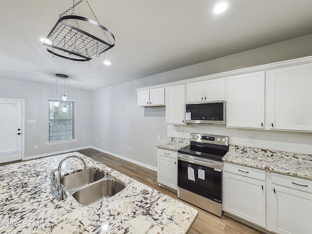 kitchen with pendant lighting, sink, white cabinetry, light wood-type flooring, and appliances with stainless steel finishes