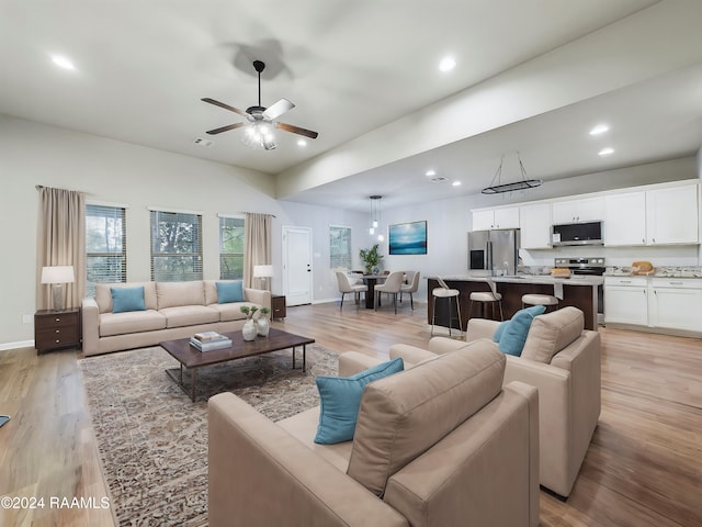 living room with light wood-type flooring, ceiling fan, and sink