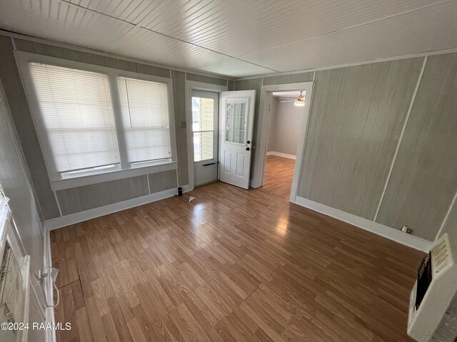 empty room featuring wooden walls, wood-type flooring, and ceiling fan