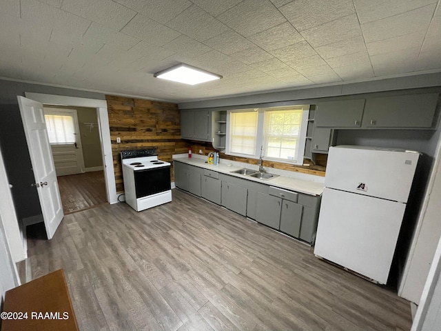 kitchen with hardwood / wood-style flooring, wooden walls, sink, and white appliances