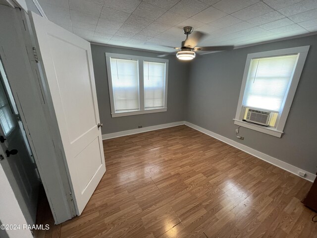 empty room with hardwood / wood-style floors, cooling unit, and ceiling fan