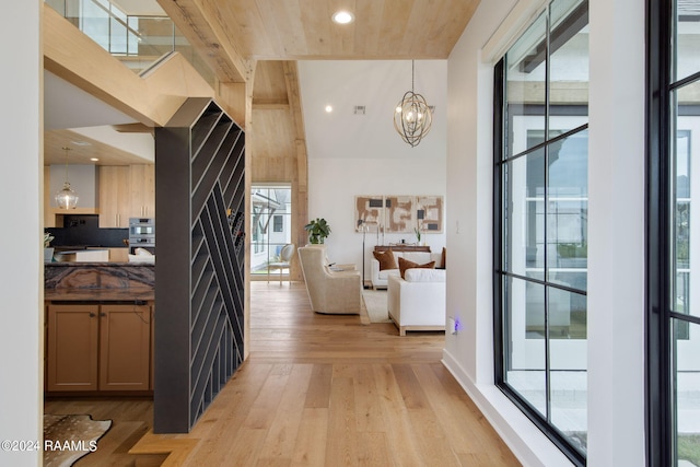 hall featuring a wealth of natural light, light hardwood / wood-style flooring, and a notable chandelier