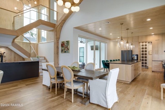 dining area featuring plenty of natural light, a chandelier, light hardwood / wood-style flooring, and a high ceiling