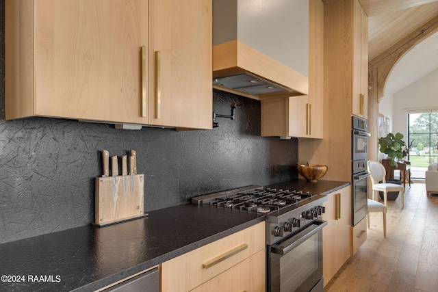 kitchen featuring light brown cabinetry, custom range hood, light hardwood / wood-style flooring, stainless steel range, and tasteful backsplash