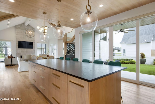 kitchen with pendant lighting, light brown cabinetry, ceiling fan with notable chandelier, and light hardwood / wood-style floors