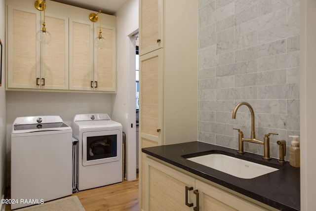 laundry room with washer and dryer, cabinets, sink, and light hardwood / wood-style floors