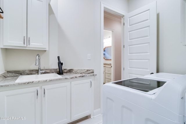 laundry area with washing machine and dryer, cabinets, and sink