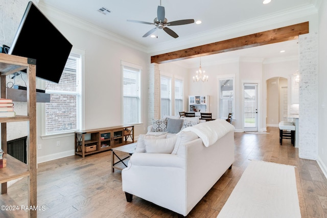 living room featuring ceiling fan with notable chandelier, a fireplace, light hardwood / wood-style flooring, beam ceiling, and crown molding