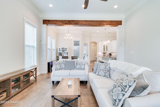 living room with light wood-type flooring, ceiling fan with notable chandelier, ornamental molding, and sink