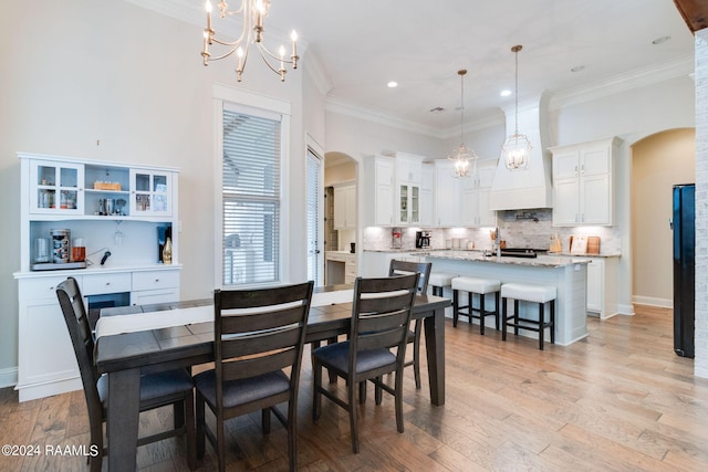 dining space featuring light wood-type flooring, crown molding, and an inviting chandelier