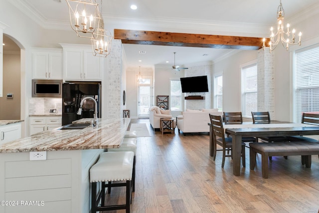 dining room with a fireplace, ceiling fan with notable chandelier, crown molding, light hardwood / wood-style flooring, and sink