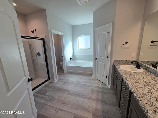 full bathroom with plus walk in shower, vanity, hardwood / wood-style flooring, and toilet