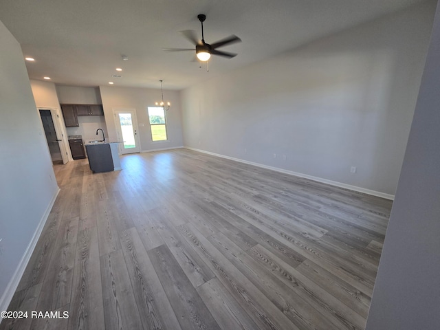 unfurnished living room featuring ceiling fan with notable chandelier, hardwood / wood-style flooring, and sink