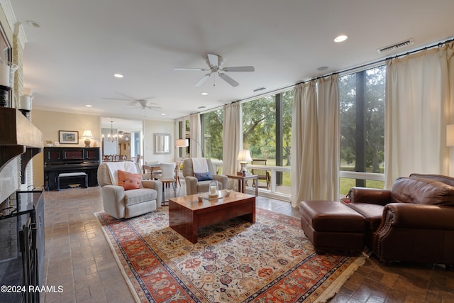 living room with a wall of windows, a fireplace, and ceiling fan with notable chandelier