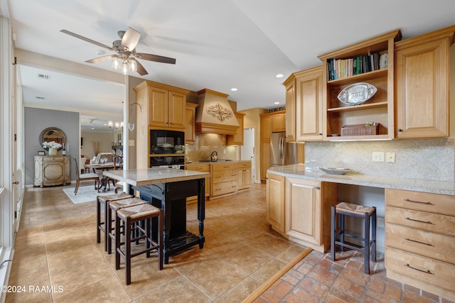 kitchen featuring black appliances, a breakfast bar, light stone counters, ceiling fan with notable chandelier, and tasteful backsplash