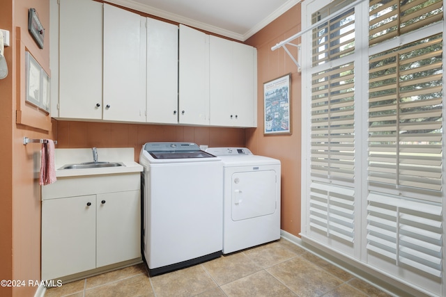 clothes washing area featuring washer and dryer, light tile patterned floors, sink, ornamental molding, and cabinets