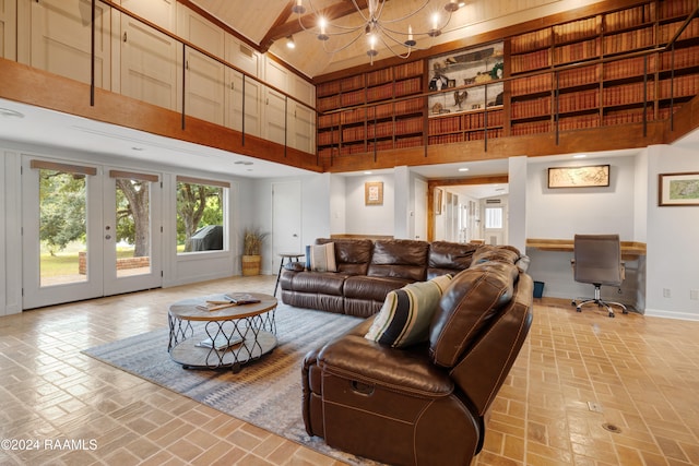 living room with built in desk, a towering ceiling, an inviting chandelier, and french doors