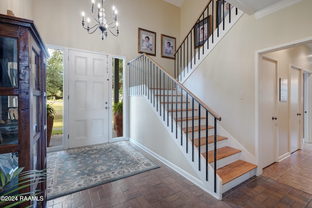 foyer entrance with crown molding, a notable chandelier, and a towering ceiling