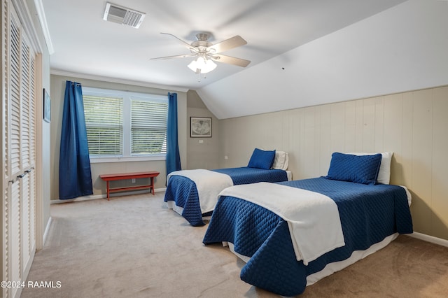 bedroom featuring a closet, ceiling fan, light carpet, lofted ceiling, and wooden walls