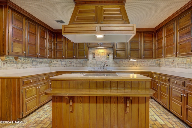 kitchen with a breakfast bar, sink, decorative backsplash, and a center island