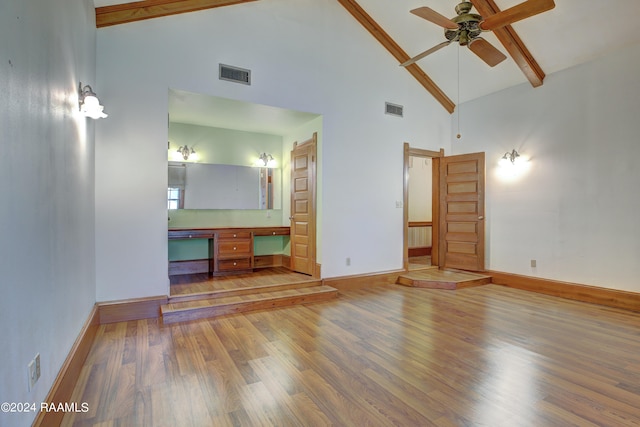 unfurnished living room featuring ceiling fan, wood-type flooring, beam ceiling, and high vaulted ceiling