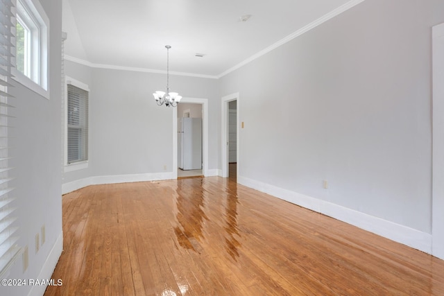 unfurnished room featuring wood-type flooring, a chandelier, and crown molding