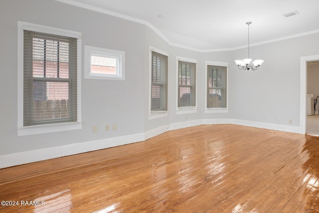 empty room with hardwood / wood-style flooring, a chandelier, and crown molding