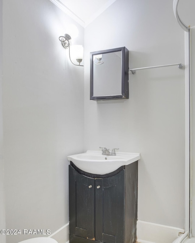 bathroom with crown molding, vanity, and vaulted ceiling