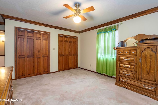 bedroom featuring light carpet, a textured ceiling, ornamental molding, and ceiling fan