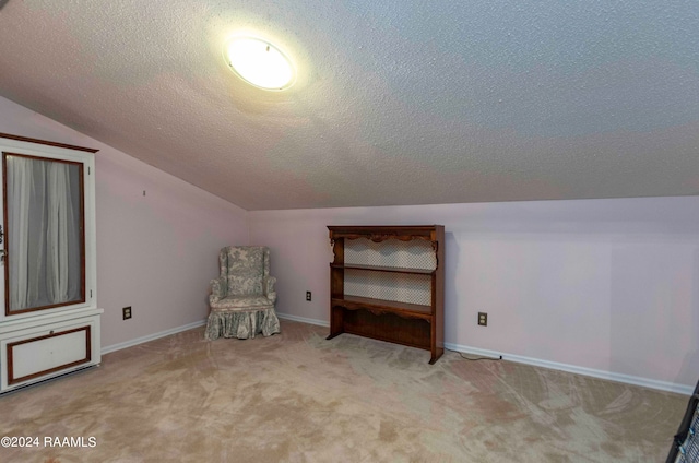 unfurnished room with a textured ceiling, vaulted ceiling, and light colored carpet